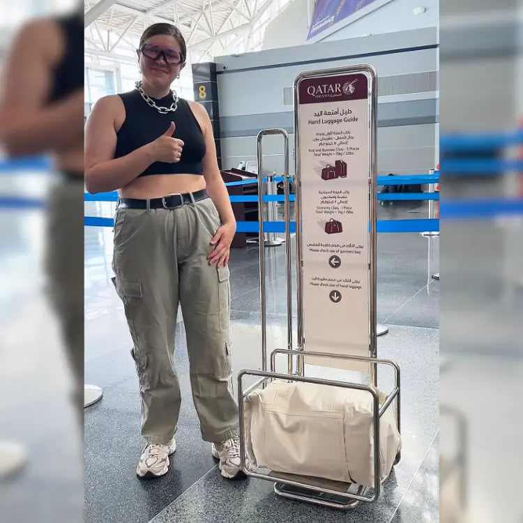 Person at an airport with a Qatar Airways luggage guide sign
