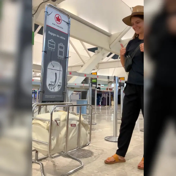 Person standing in an airport with a sign indicating luggage rules.