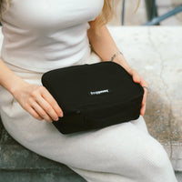 Person holding a black travel case on a bench.
