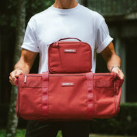 Person holding two red bags outdoors