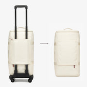 White rolling suitcase and backpack side by side on a plain background