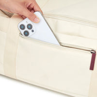 Hand placing a phone into a beige bag.