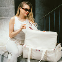 Woman sitting on steps holding a white bag with a red label.